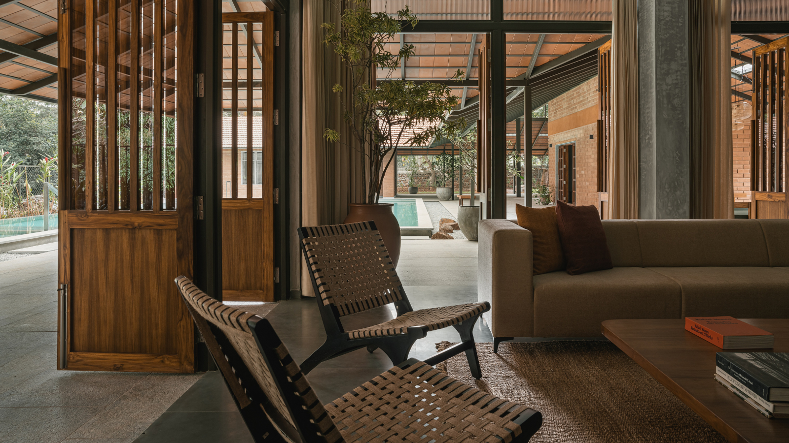 Luxury farmhouse interior with wooden doors, stylish lounge chairs, sofa, and a private pool view.