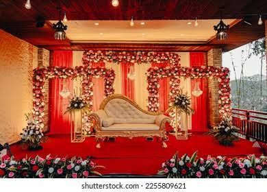 **Alt text:** Modern luxury farmhouse wedding venue with floral stage decoration, green lawn, and tropical trees.